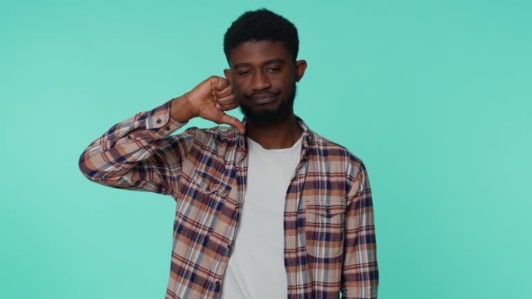Upset man in casual shirt showing thumbs down sign gesture, disapproval, dissatisfied dislike