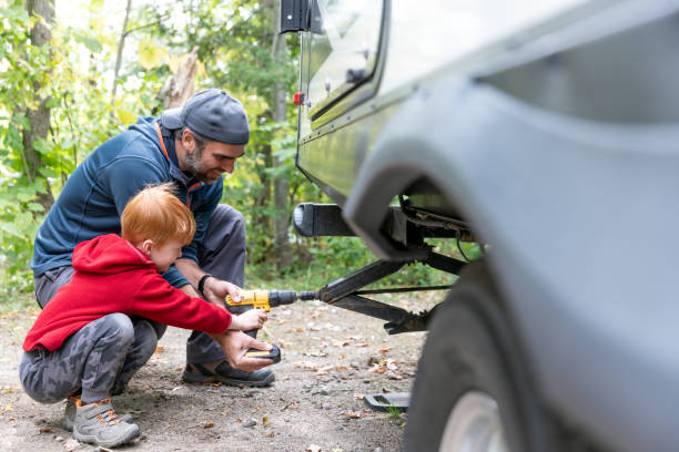 istock Father and Son Deploying Stabilizer of Camper Trailer on Campground in Summer 1375485898