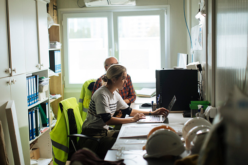 Beautiful young female working in her office at the construction site