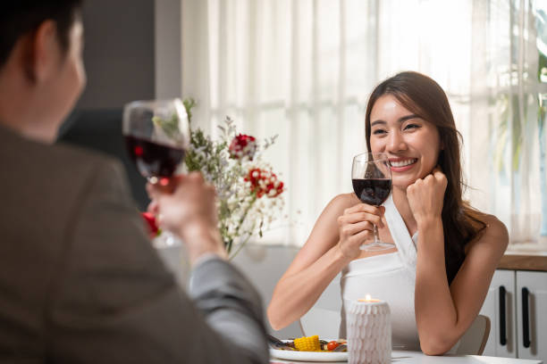 함께 발렌타인 데이를 축하하기 위해 저녁 식사를하는 아시아 젊은 부부. 매력적인 로맨틱 한 새로운 결혼 남자와 여자 밤 파티 집에서 부엌에서 결혼 기념일에 대 한 테이블에 음식을 먹는다. - honeymoon color image horizontal setting the table 뉴스 사진 이미지