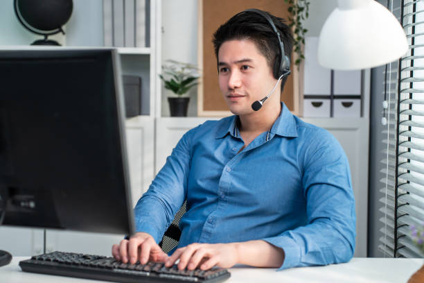 istock Asian handsome business man using laptop computer working in office. Attractive professional male employee call center sitting on table, wear headset talk and support customer in corporate workplace. 1375555953