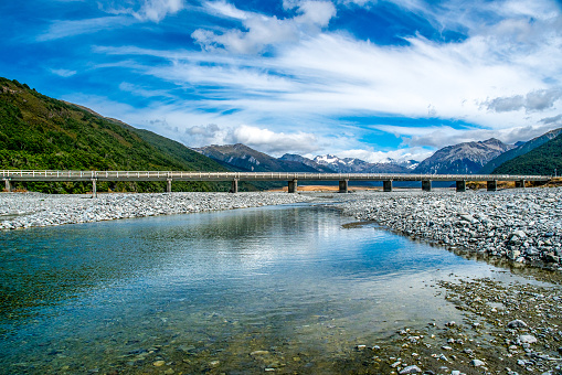 Arthurs Pass  bridge crossing the  Waimakariri River with a backdrop of the snow covered Southern alps mountain range