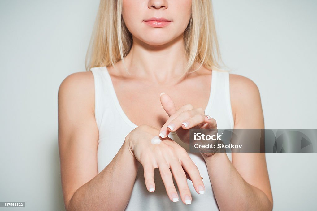Young beautiful woman applying moisturizing cream to her hands Female applying moisturizing cream to her hands with a nice french manicure Adult Stock Photo