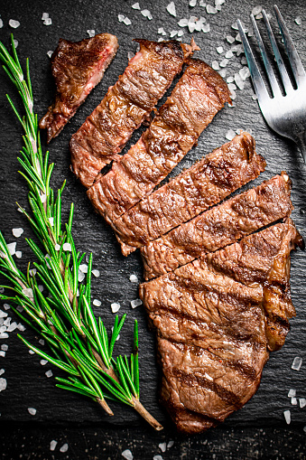 Grilled steak with a sprig of rosemary. On a black background. High quality photo