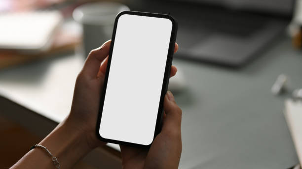 istock Smartphone mockup is in a women's hands over office desk. 1375605776