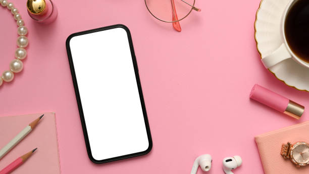 istock Feminine office desk with smartphone mockup on pink background. 1375606297