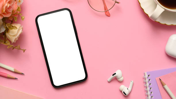istock Pink office desk workspace with smartphone mockup and office stuff. 1375606302