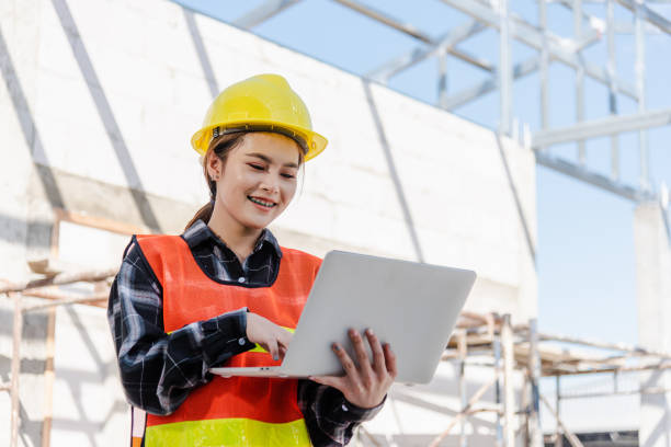 istock Asian engineer architect worker woman holding laptop inspect and oversee infrastructure progress at construction site 1375607375