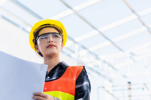 istock Asian engineer architect worker woman holding blueprint infrastructure progress at construction site 1375607377