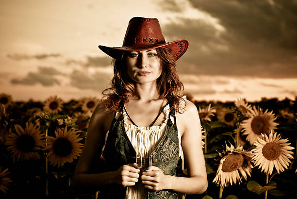 Cowgirl against a brick wall tips hat. Shot in Midway City, California.