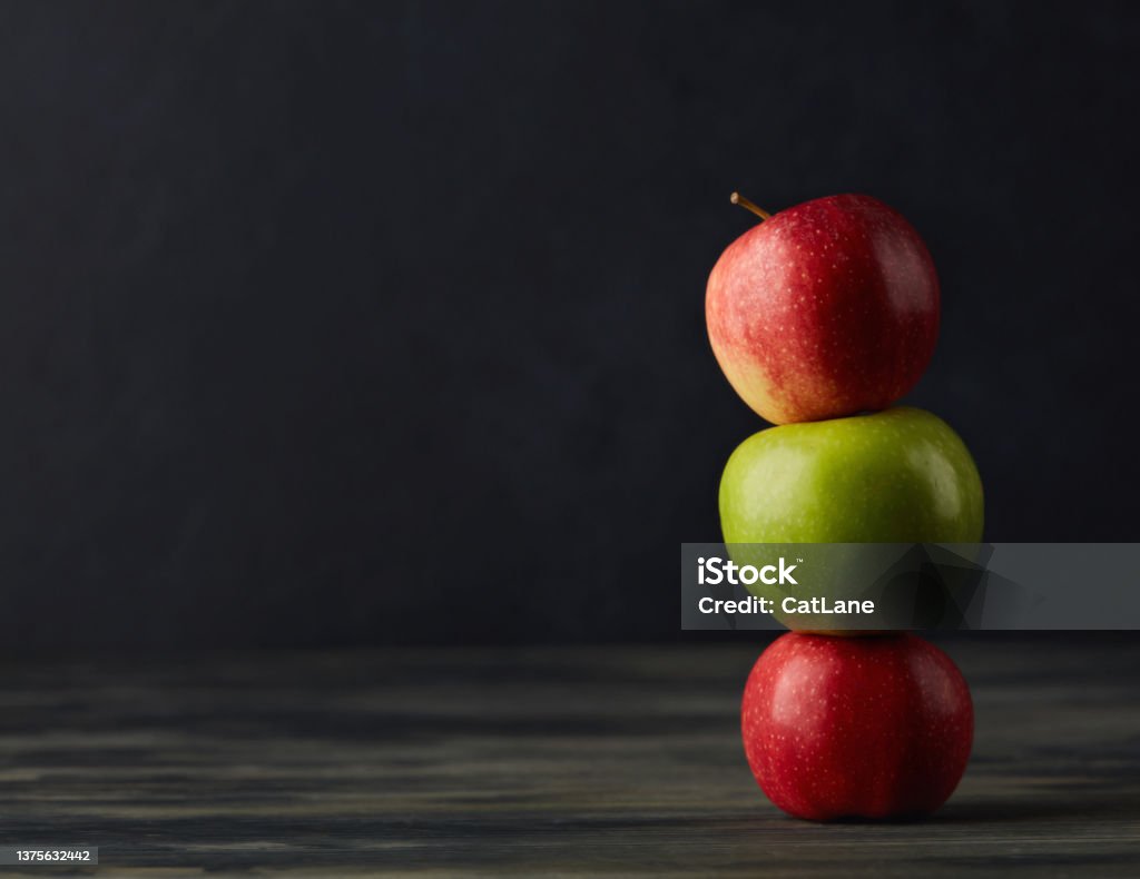 Still life with apples stacked together on a dark rustic table Apple - Fruit Stock Photo