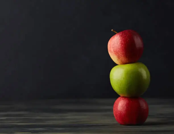 Photo of Still life with apples stacked together on a dark rustic table