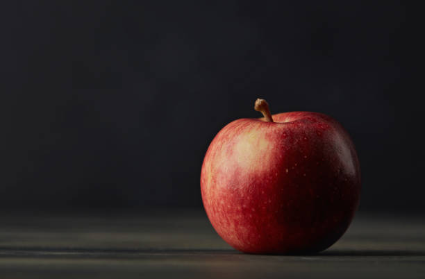 暗い素朴なテーブルの上に単一の赤いリンゴを持つ静物画 - apple gala apple fuji apple fruit ストックフォトと画像