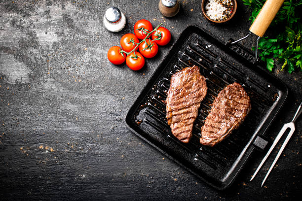 grilled steak in a frying pan with tomatoes and spices. - top sirloin imagens e fotografias de stock