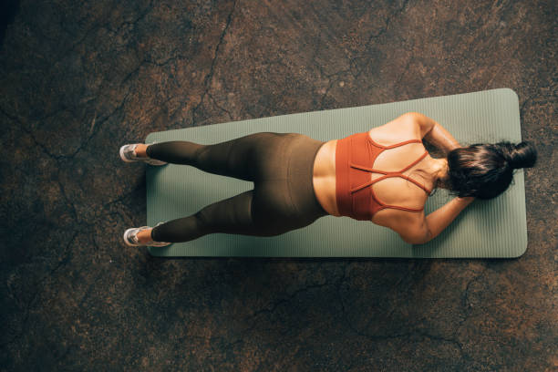Anonymous Caucasian Sportswoman Doing Plank on a Yoga Mat A strong unrecognizable woman holding a plank position on a yoga mat. ripl fitness