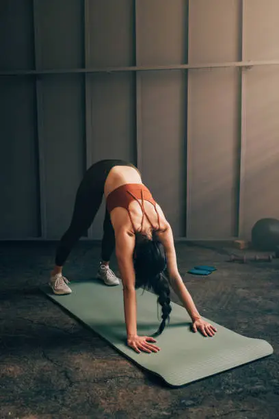 Photo of Anonymous Caucasian Woman in a Downward Facing Dog Position on a Yoga Mat
