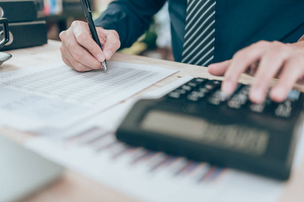istock Accountant writing and checking while working on calculator to calculate company data, document and report on desk office. Accounting business concept. 1375693316
