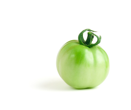 An unripe green tomato on a pure white background.