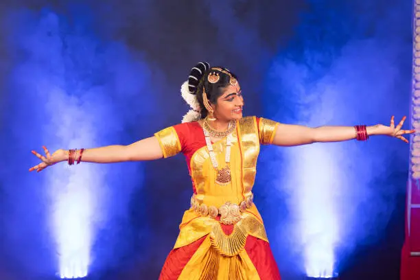 Photo of Smiling indian bharatanatyam dancer on stage performing dance with hands gesture - conapt of artist, Traditional Indian culture and clasic dancer.