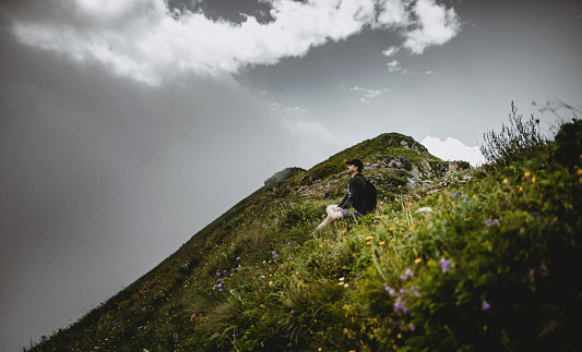 Tourist sitting on the grass in the mountains