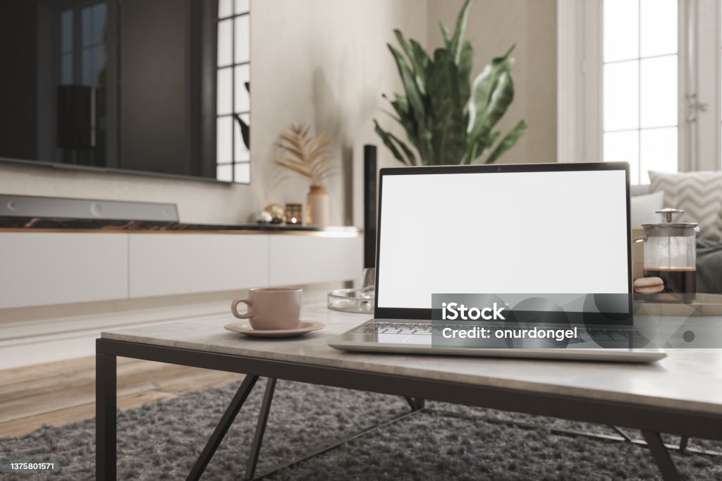 Working At Home. Laptop With Blank Screen On Coffee Table With Living Room Background. Computer Stock Photo