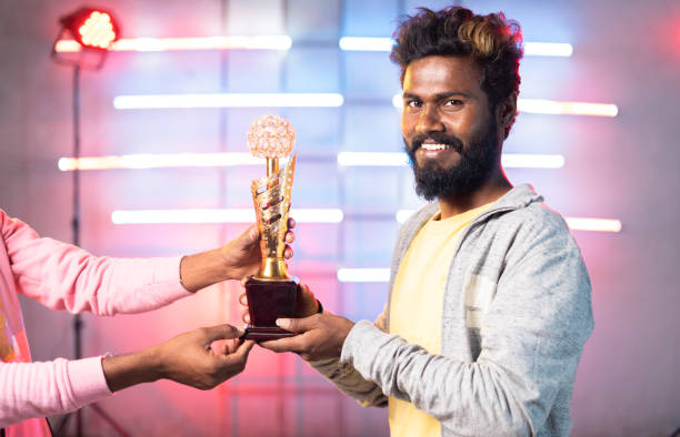 istock Excited dancer receving winner trophy in dancing compitation on stage by looking at camera - concept of successful, proud, achievement and accomplishment. 1375827117