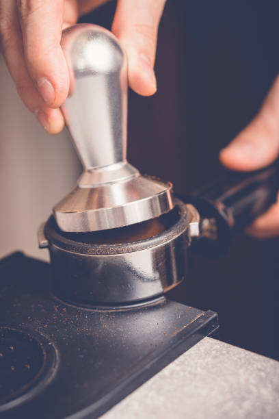 barista manomissione caffè in portafiltro usando tamper. processo di preparazione del caffè fresco ravvicinato - tampering foto e immagini stock