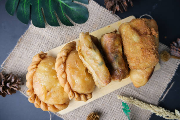 istock Several type of Indonesian fried snack: pastel, martabak, risol, and molen on cutting board with ornament and black background 1375853051