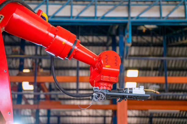 Employees are working at factory with robotic arms. Blue collar workers and technology concept,