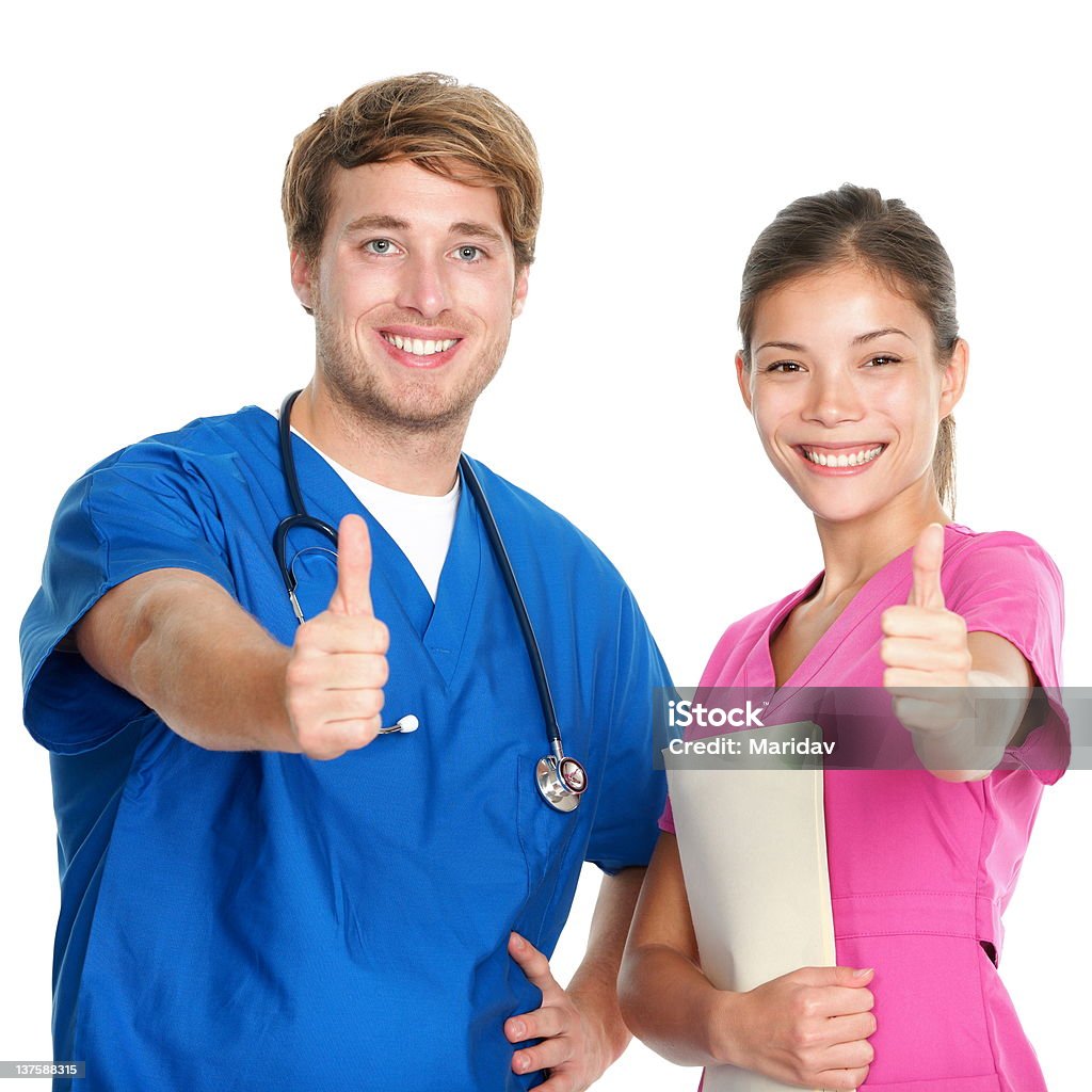 Nurse and doctor team happy thumbs up Nurse and doctor team giving happy thumbs up smiling joyful at camera. Young medical professionals isolated on white background. Asian woman and Caucasian man in their 20s. See more: Male Nurse Stock Photo