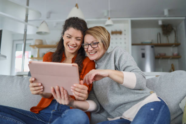 Mother and daughter using tablet at home stock photo