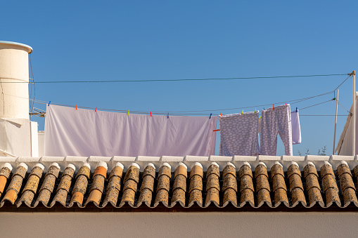View of roof tiles and rooftop porch with bedclothes and laundry hanging out to dry