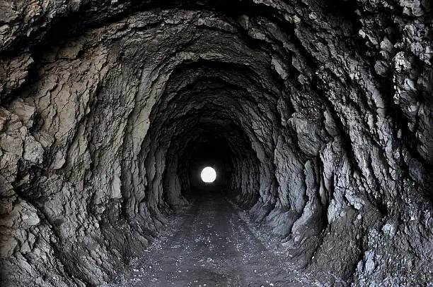 tunnel dug into heavy rock with a lightspot at the end