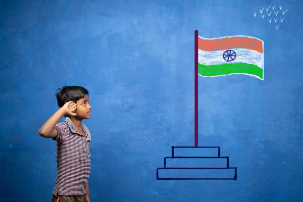 niño pequeño saludando estar viendo la bandera india en la pared - concepto de patriotismo, pobreza y celebración del día de la independencia en la india - child patriotism saluting flag fotografías e imágenes de stock