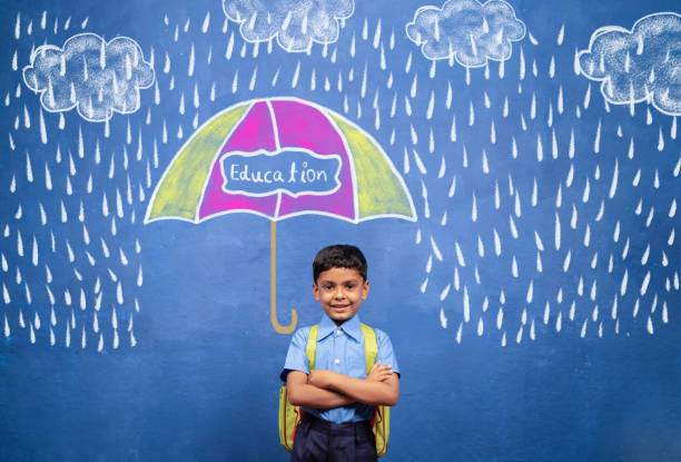 concept of security, growth and development from education showing by Happy smiling kid standing under rain with protection from umbrella with education on it.