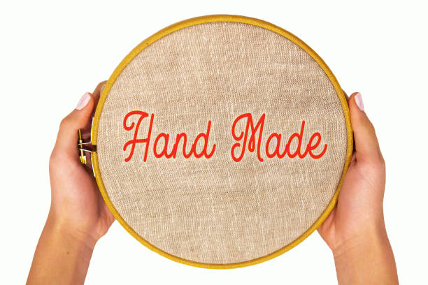 Embroidery hoop with natural linen fabric in women's hands, isolate. Template with text - hand made, top of view.