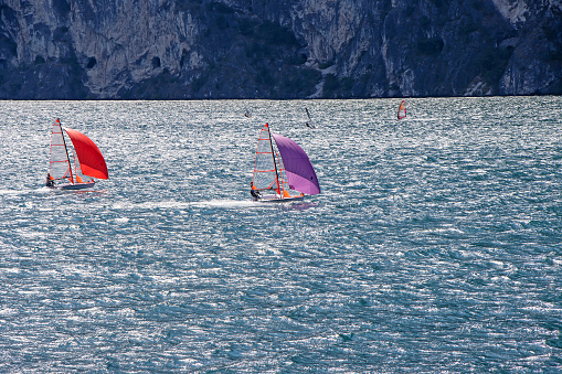 Small sailboats sail on Lake Lago di Garda in Italy