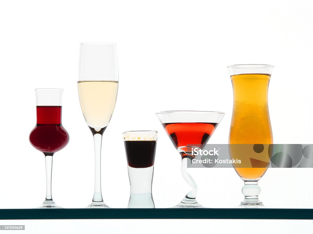 Mismatched drinking glasses with colored liquid White background Alcohol - Drink Stock Photo