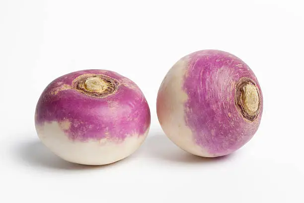 Two whole fresh purple headed turnips on white background