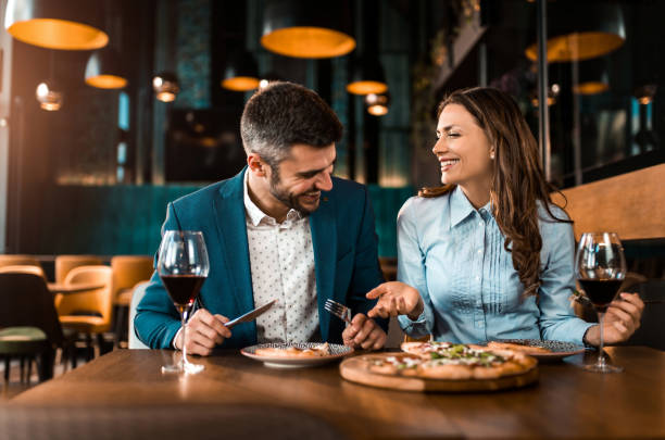 Playful couple eating pizza together in a restaurant. stock photo