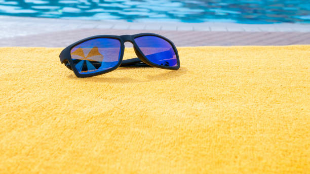 lunettes de soleil piscine fond d’été. équipement de piscine de plage avec lunettes de soleil de voyage sur serviette de vacances jaune. lunettes de soleil près de la piscine, concept de vacances. - deck chair photos et images de collection