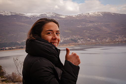 portrait of a woman showing thumb up on the edge of lake ohrid in winter
