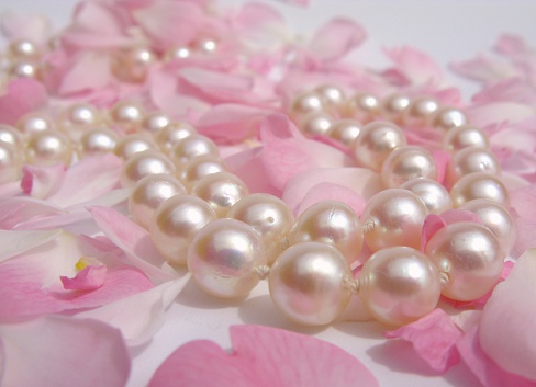 Closeup of multicolored pearl beads on a woman in front of yellow background. Selective focus.