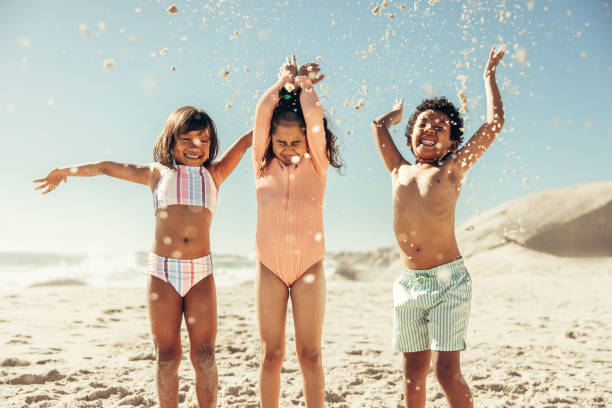 istock Adorable little kids throwing beach sand into the air 1375964892