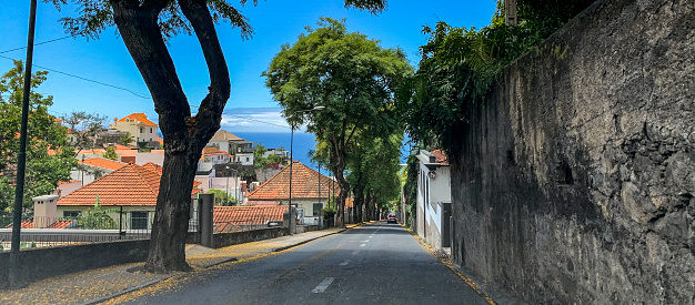View over the rooftops of Funchal while driving on the streets of the capitol of Madeira island during a beautiful summer day with the mountains on one side and the ocean on the other.