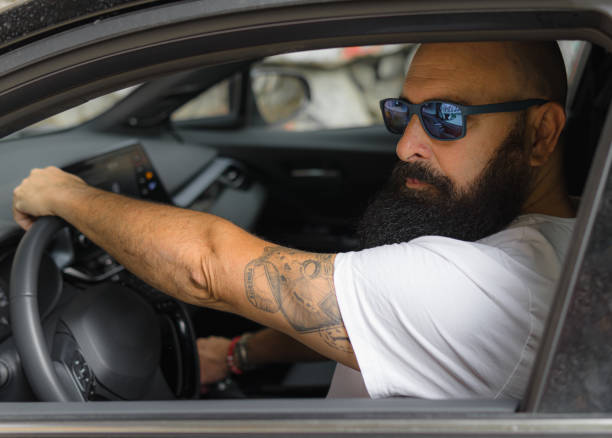 istock nice bald man wearing sunglasses sitting on a drivers seat holding with his hands the steering wheel 1375989846