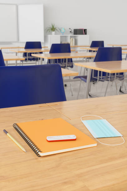 istock Empty Classroom Interior With COVID-19 Rapid Test, Protective Face Mask And Notebook On Wooden Desk. 1376007422