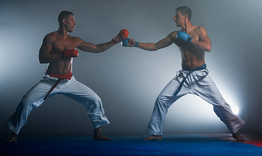 Waist up of aged 20-29 years old with brown hair caucasian male standing in front of white background wearing glove who is excited and cheering and showing fist who is and doing fist pump