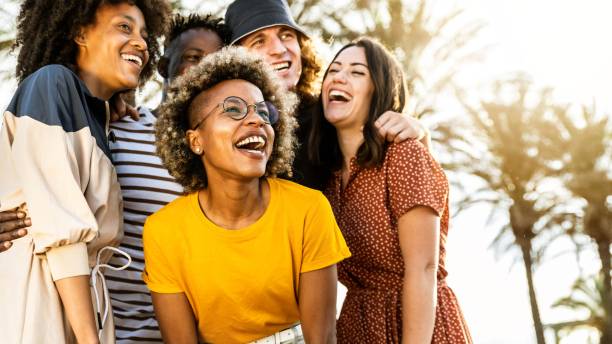 Young people laughing out loud on a sunny day - Cheerful group of best friends enjoying summer vacation together - Human resources, youth lifestyle and summertime holidays concept stock photo