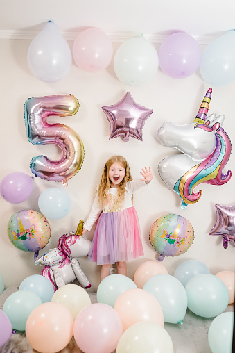 Happy girl celebrates her birthday. Party decoration with balloons in the style unicorn, rainbow, my little pony. Birthday party for 5 years. Idea for decorating party.